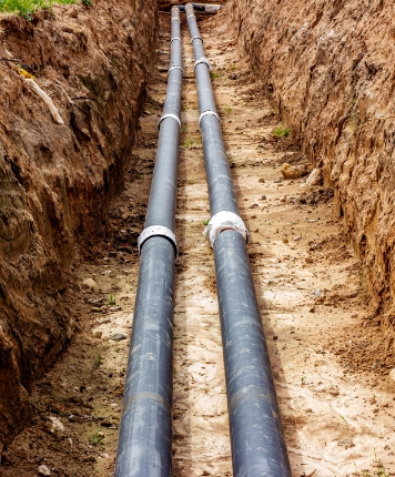 Open trench with two pipes on the ground